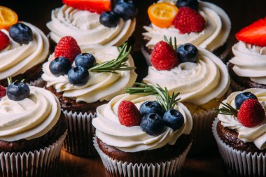 Çilek ile taze ve lezzetli çikolata cupcakes. Seçici odak. Koyu ahşap arka plan. Rustik tarzı, metin için yer.