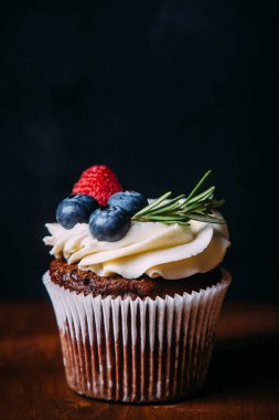 Çilek ile taze ve lezzetli çikolata cupcakes. Seçici odak. Koyu ahşap arka plan. Rustik tarzı, metin için yer.