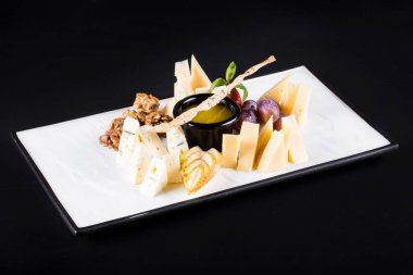 Büyük bir tabak atıştırmalık üzüm, peynir, ceviz, koyu arka plan üzerinde kraker gibi geniş bir seçki ile