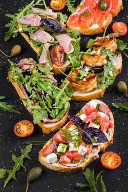 Brushetta şarap için ayarlayın. Küçük sandviç salam, domates, kaşar peyniri, taze fesleğen ile çeşitli