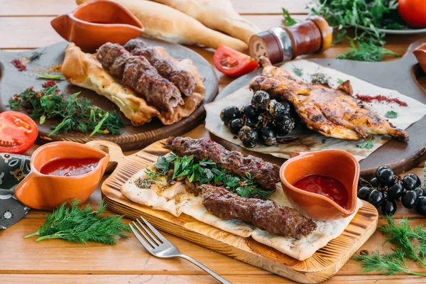 Viande hachée Lyulya kebab aux légumes frais et sauces sur une table de service. Dîner traditionnel géorgien — Photo