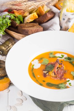 Masanın üzerinde bir rustik tarzda pastırmalı balkabağı çorbası. Ekmek ve yeşillik içinde belgili tanımlık geçmiş