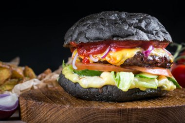 Siyah arka plan üzerine taze lezzetli burger. Sığır eti, soğan, domates, marul ve malzemelerle peynir ile ev yapımı hamburger
