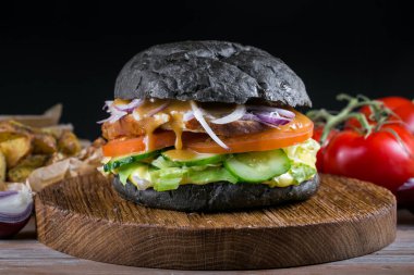 Siyah arka plan üzerine taze lezzetli burger. Ev yapımı domuz biftek hamburger soğan, domates, marul ve peynir malzemelerle