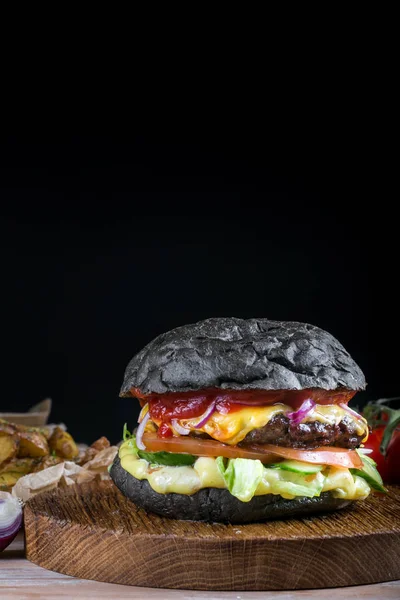 Siyah arka plan üzerine taze lezzetli burger. Sığır eti, soğan, domates, marul ve malzemelerle peynir ile ev yapımı hamburger