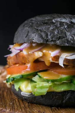 Siyah arka plan üzerine taze lezzetli burger. Ev yapımı domuz biftek hamburger soğan, domates, marul ve peynir malzemelerle