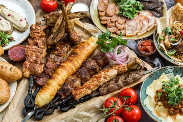 Питание на открытом воздухе. Аппетитный стейк на гриле, сосиски и овощи на деревянном столе для пикника . — стоковое фото
