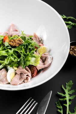 sığır eti, roka, domates, yumurta ve tahıl Siyah bir arka plan üzerine hardal salatası. yakın çekim