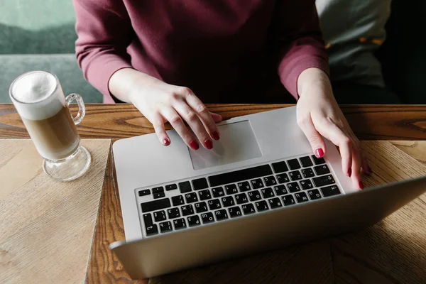 在一家咖啡馆的笔记本电脑上工作的女性。女人在家里使用笔记本电脑。使用便携式计算机互联网。在咖啡厅中使用笔记本电脑的手 — 图库照片