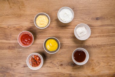 Ayarla soslar - ketçap, mayonez, hardal soya sosu, Barbekü sos, hardal taneleri ve nar sosu ahşap masa