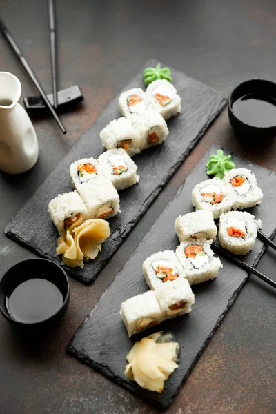 sushi for two. Set for two with chopsticks, ginger, soy, wasabi. Above view on wood background and black slate plates.