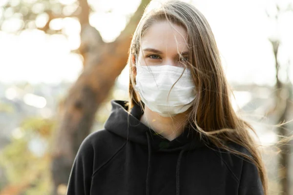 Närbild av kvinna bär skyddande ansiktsmask utomhus. Begreppet utbrott av Coronavirus covid-19. Stockbild