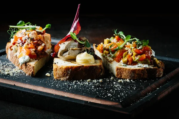 Läcker italiensk bruschetta med tomat, köttpaté, oliver, färskost. Uppsättning goda aptitretare smörgåsar. Royaltyfria Stockfoton