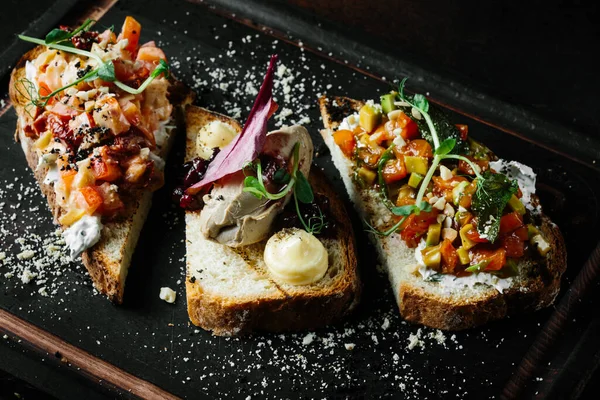 Läcker italiensk bruschetta med tomat, köttpaté, oliver, färskost. Uppsättning goda aptitretare smörgåsar. Stockfoto