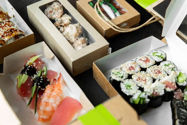 Várias seleções de sushi, rolos e gunkans em caixas de artesanato em um fundo escuro. Comida em casa. Conceito de entrega — Fotografia de Stock