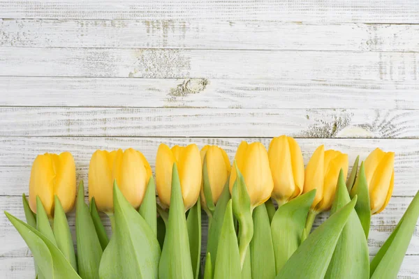 Žluté tulipány dřevěné pozadí — Stock fotografie