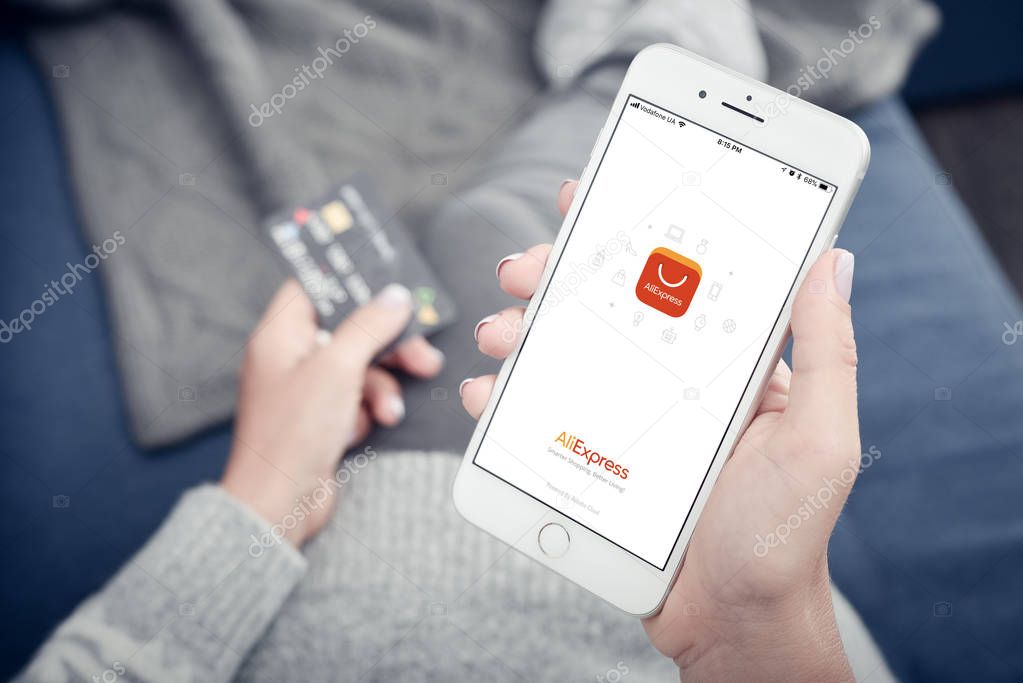 Kyiv, Ukraine - January 24, 2018: Woman holding Apple Iphone 8 plus with loading Aliexpress mobile app at home closeup.