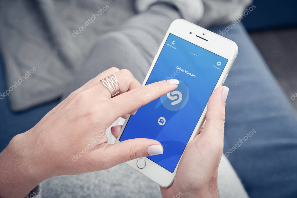 Kyiv, Ukraine - January 24, 2018:  Woman hands using Shazam application on Apple Iphone 8 plus for searching music what she like while lying at home on the couch. Close up.