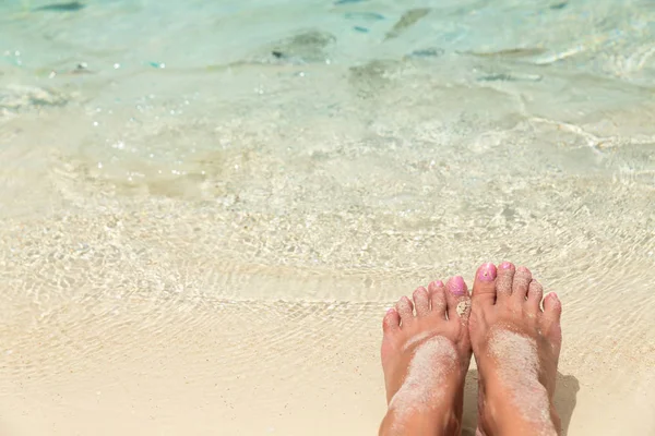 Kale vrouwelijke voeten in het water van de zee met kleine tropische fis — Stockfoto