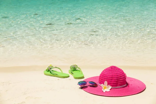 Большая розовая пляжная шляпа, солнцезащитные очки и зеленые тапочки в золоте — стоковое фото