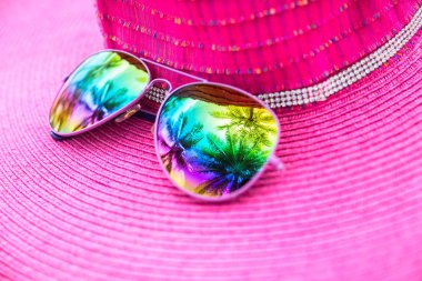 Pink summer hat and colorful sunglasses with palm tree reflectio clipart
