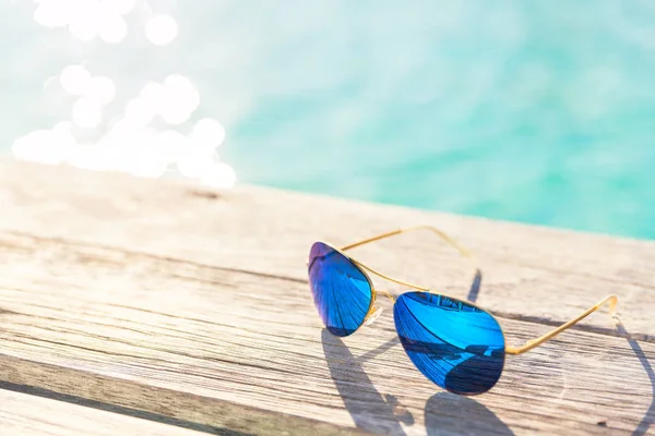 Blie Sunglasses on wooden decking by seaside — Stock Photo, Image