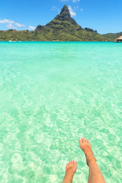 Female crossed legs over tropical blue lagoon and Otemanu mount, Stock Picture