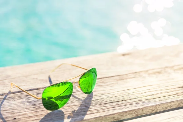 Óculos de sol verdes em um deck de madeira, conceito de férias de verão — Fotografia de Stock