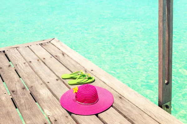 Grande cappello da sole rosa e sandalo sul ponte vicino al mare — Foto Stock