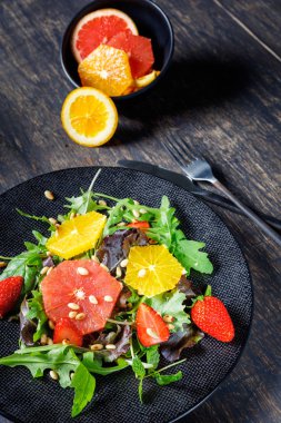 Greyfurt ve portakal karışımı salata ile çam fıstığı siyah plaka üzerinde bir