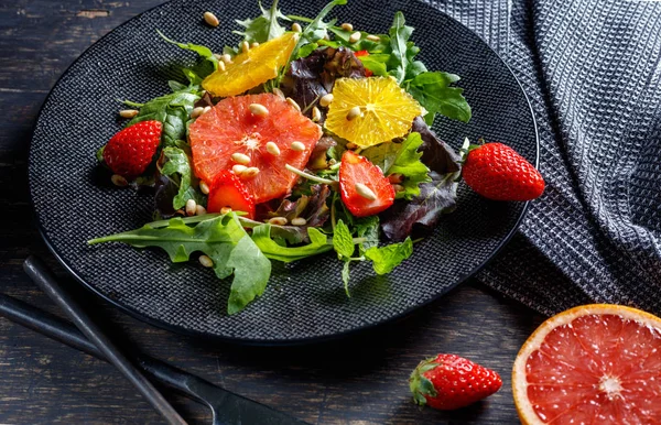 Ensalada de pomelo y naranja mezcla con piñones en plato negro un —  Fotos de Stock