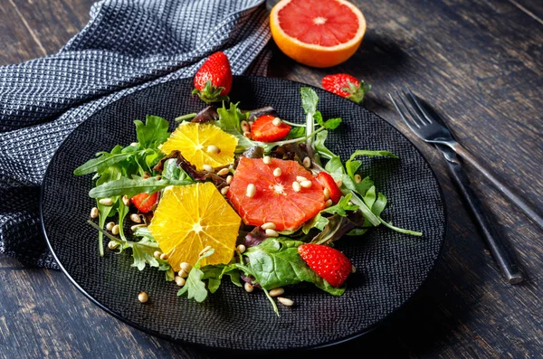 Ensalada de pomelo y naranja mezcla con piñones en plato negro un —  Fotos de Stock