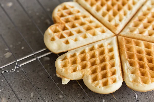Freshly backed waffles in shape of heart, resting on metal rack — Stock Photo, Image