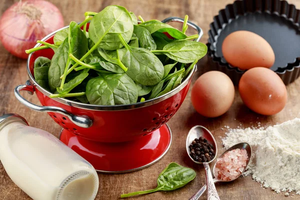 Fresh spinach in red colander and ingredients to cook spinach qu — Stock Photo, Image