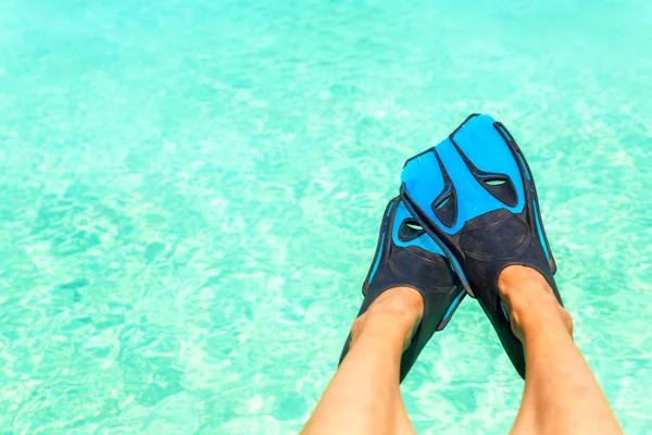 Ženské nohy s modrou nepotápíte ploutve nad tyrkysově modrou vodou — Stock fotografie