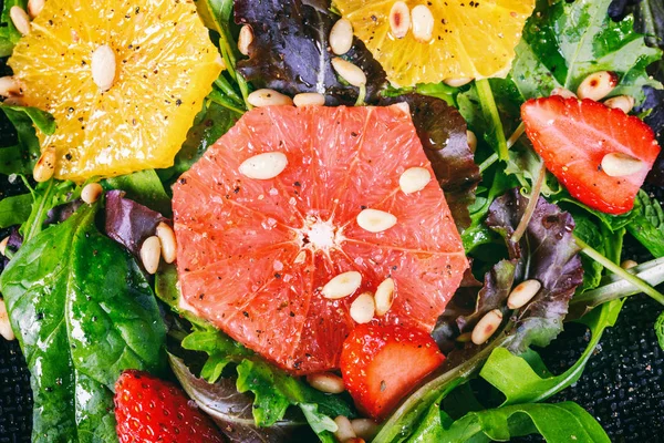 Grapefruit-Orangen-Mix-Salat mit Pinienkernen auf schwarzem Teller, — Stockfoto