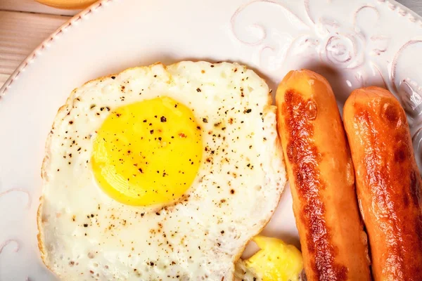 Desayuno de huevos soleados boca arriba, salchichas fritas en redondo blanco p — Foto de Stock