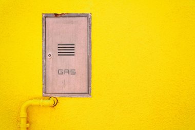 Gaz borusu ve parlak sarı duvarındaki bir kuyu