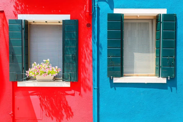 Malebné okna s okenicemi, na červené a modré zdi na fa — Stock fotografie
