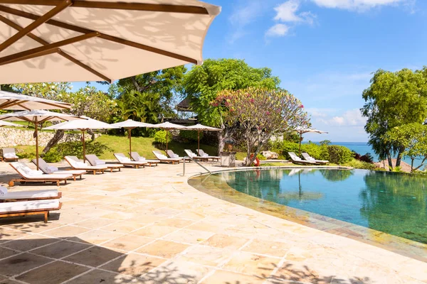 Bella piscina tropicale con lettini e ombrelloni — Foto Stock
