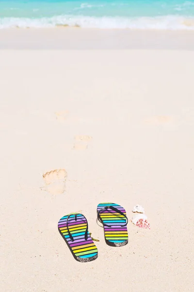 Chanclas multicolores y gafas de sol en una playa soleada — Foto de Stock