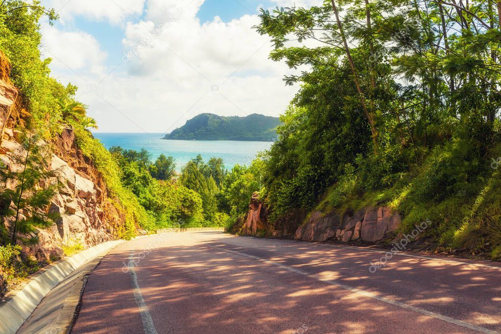 Empty tropical road leading to ocean's beach in Mahe island, Sey