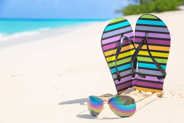 Infradito multicolore e occhiali da sole su una spiaggia soleggiata di Seych — Foto Stock