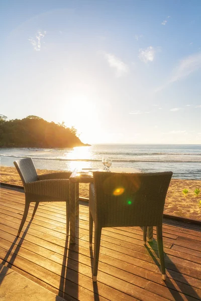 Dining table and two chairs on decking by sea side at evening su — Stock Photo, Image