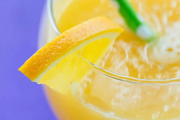Macro shot de jugo de naranja recién exprimido sobre fondo púrpura — Foto de Stock