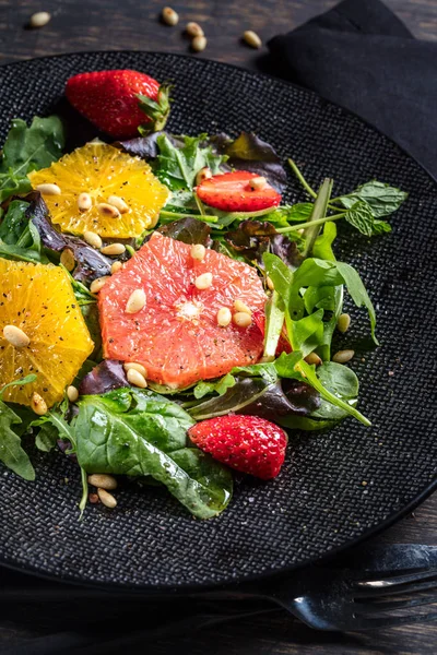 Grapefruit-Orangen-Mix-Salat mit Pinienkernen auf schwarzem Teller — Stockfoto