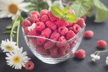 Cam kasede kırmızı ahududular ve tarla çiçekleri.