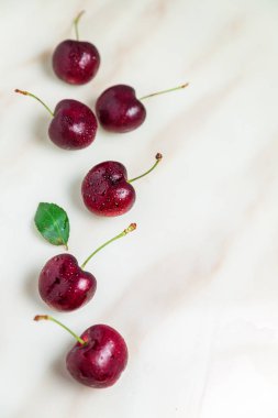 Beyaz mermer sekme masasında sulu kırmızı kirazlar, üst görünüm, döndür