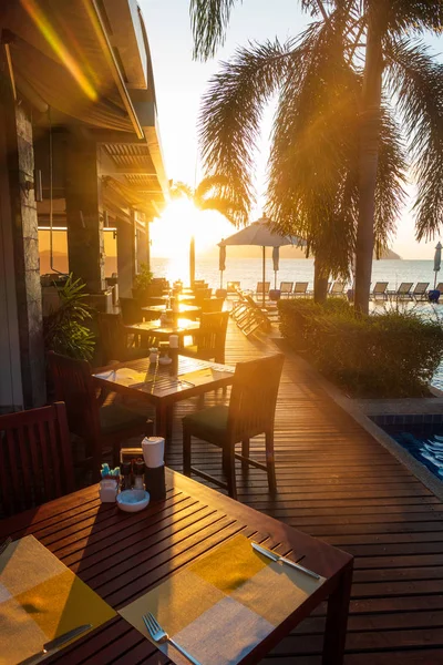 Table and chairs on wooden decking at early sunrise by seaside, vertical composition — ストック写真