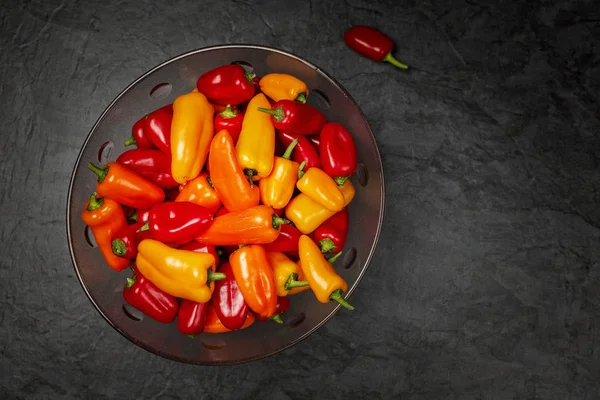 Mélange de mini poivrons colorés dans un bol en verre sur fond sombre — Photo